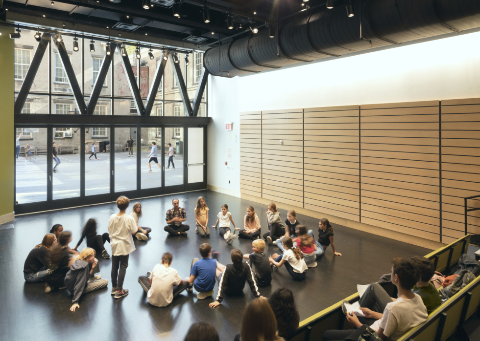 The great room at Friends Seminary School in New York features telescoping benches, teak wall paneling, and retractable Nana Wall glass windows.